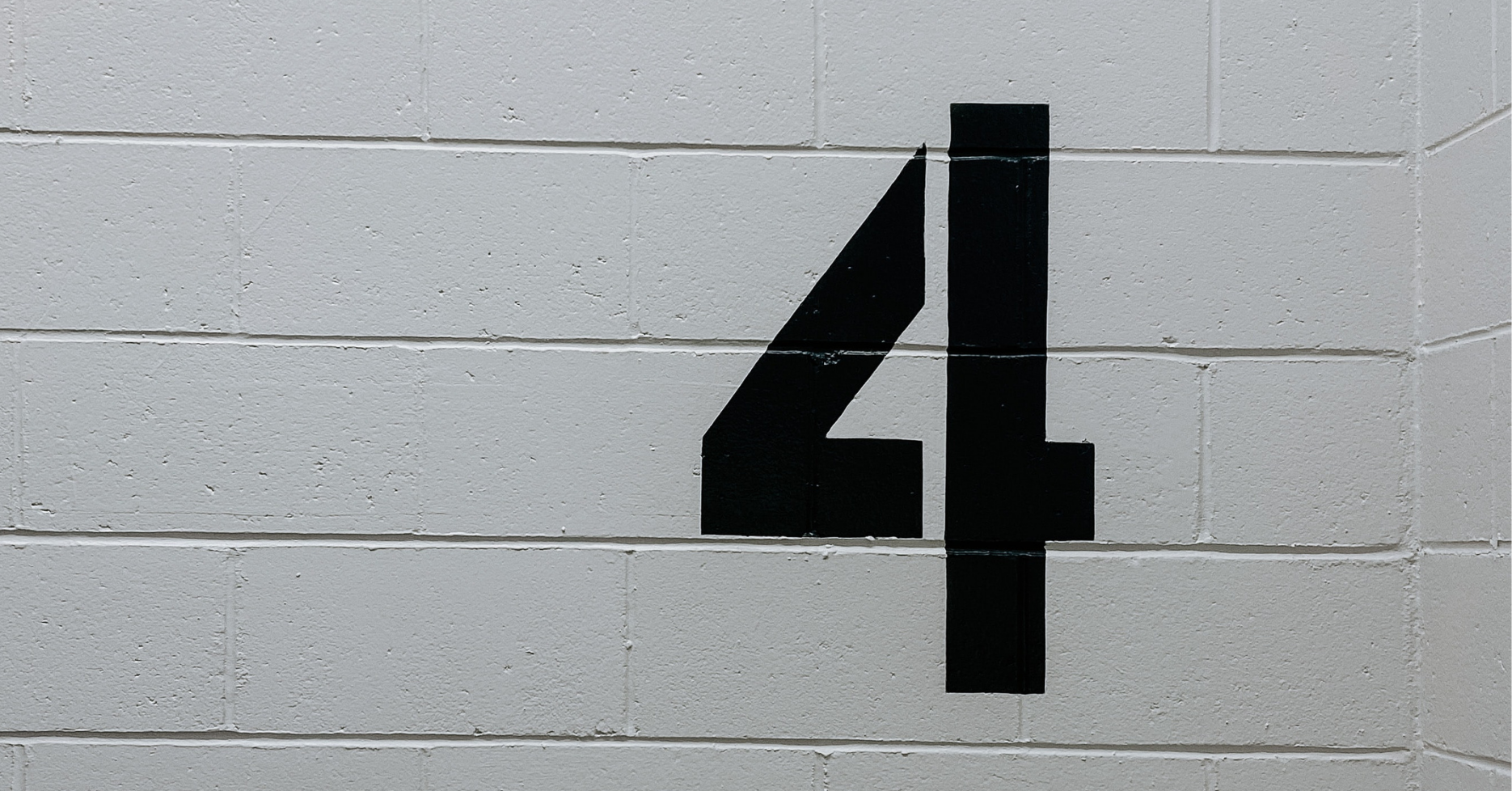 the number four on a white painted blockwork wall